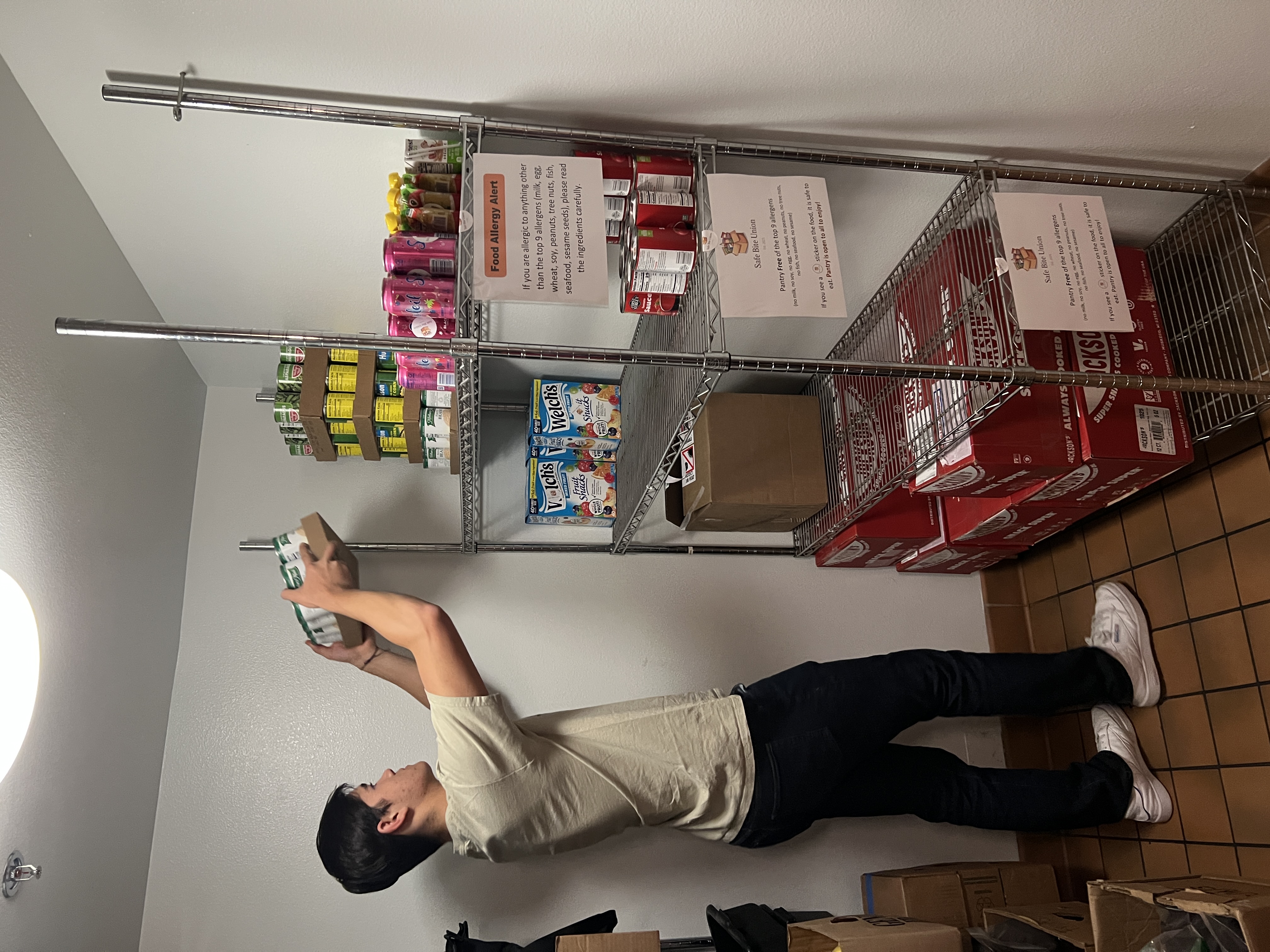Volunteer stocking shelves with allergy alert signs